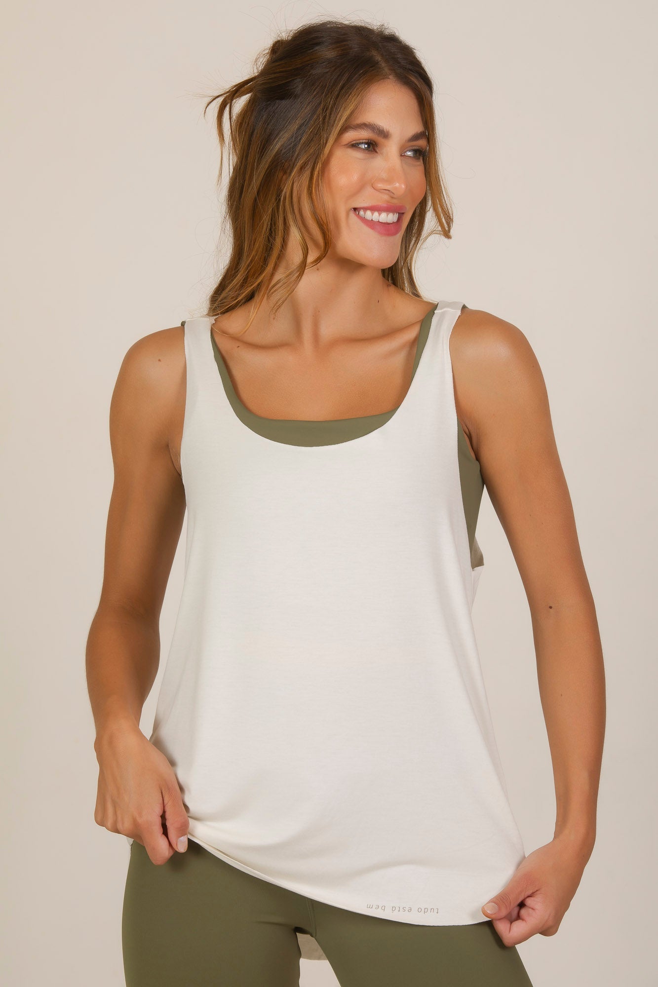 Woman wearing a lightweight Over Tank Top in neutral color, showcasing its oversized fit and sporty style.